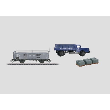 Zweiachsiger Schiebedachwagen der Bauart Kmmks 51, mit Bremserhaus. Privatwagen der Firma Albrecht Braun, Lonsee. Eingestellt bei der Deutschen Bundesbahn (DB). LKW Büssing mit Pritsche der Firma Braun, mit Steinplatten als Beladung. 